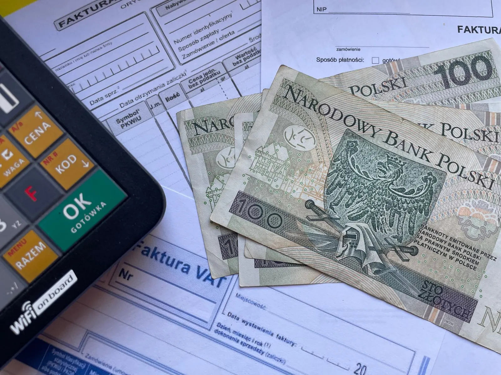 Devises polonaises apposées sur des factures avec une calculatrice, illustrant le calcul de la TVA en micro-entreprise