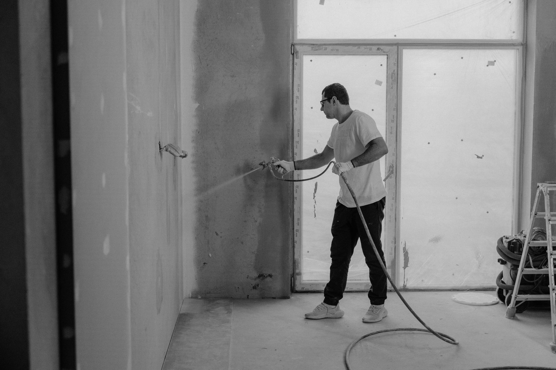 Ouvrier peignant un mur intérieur lors de travaux de rénovation.