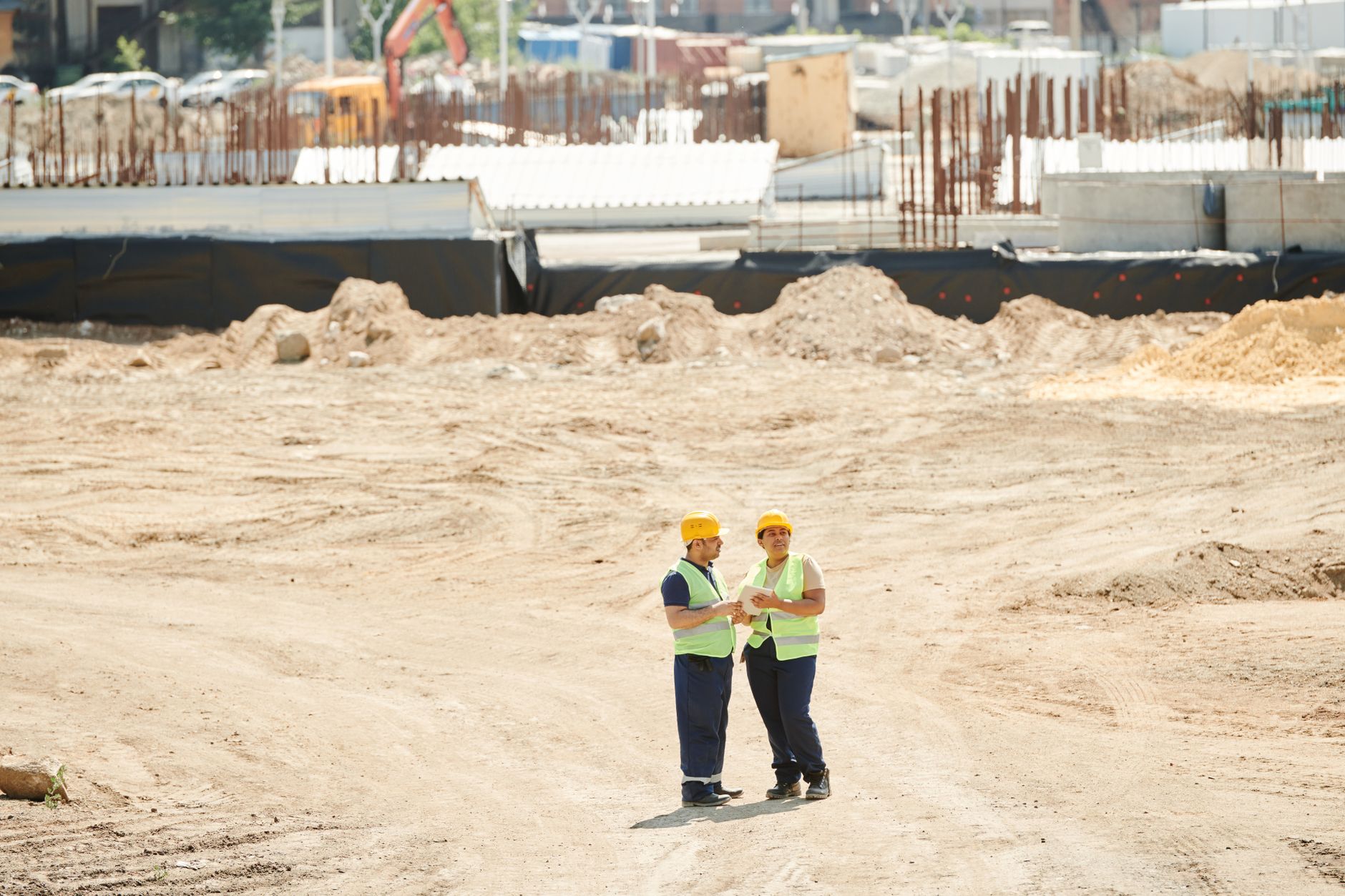 Deux professionnels du bâtiment échangent sur un chantier en tenue de sécurité.
