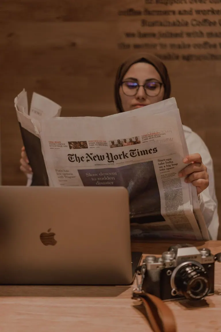 Quickote VS Tiime — une indépendante lit la presse dans un café à côté de son ordinateur portable