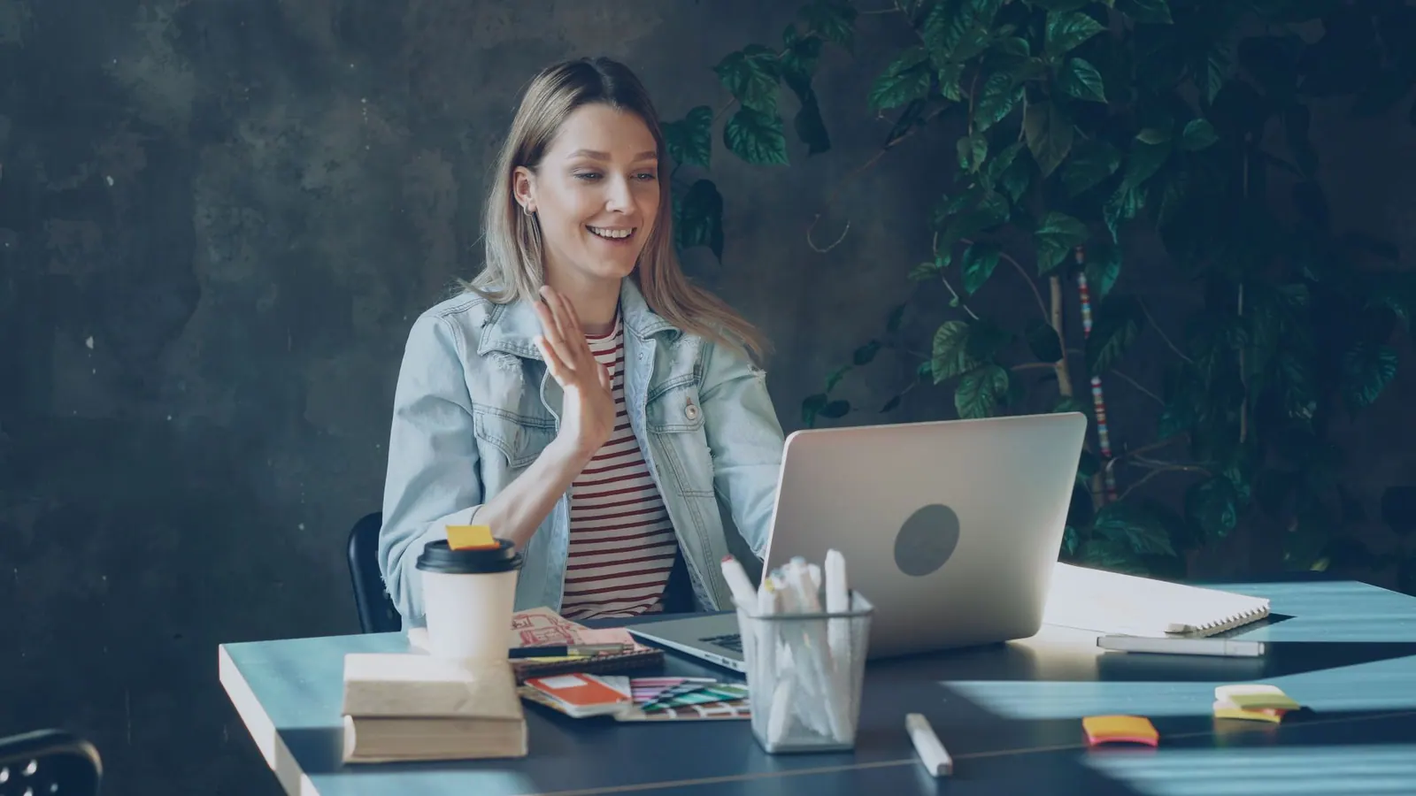 Quickote vs Pennylane — une femme souriante durant un appel vidéo à son espace de travail avec un portable et un café