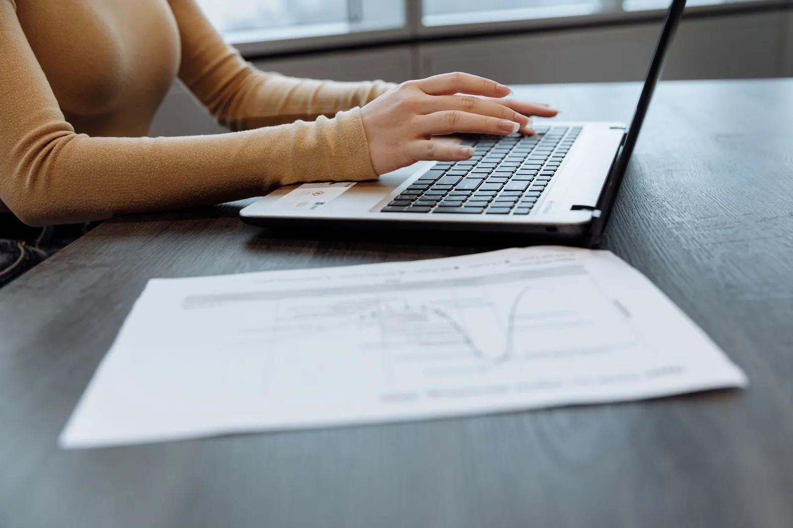 Gros plan sur les mains d'une personne tapant sur un ordinateur portable sur un bureau avec des documents. Idéal pour des Gros plan sur les mains d'une personne tapant sur un ordinateur portable sur un bureau avec des documents. Idéal pour des