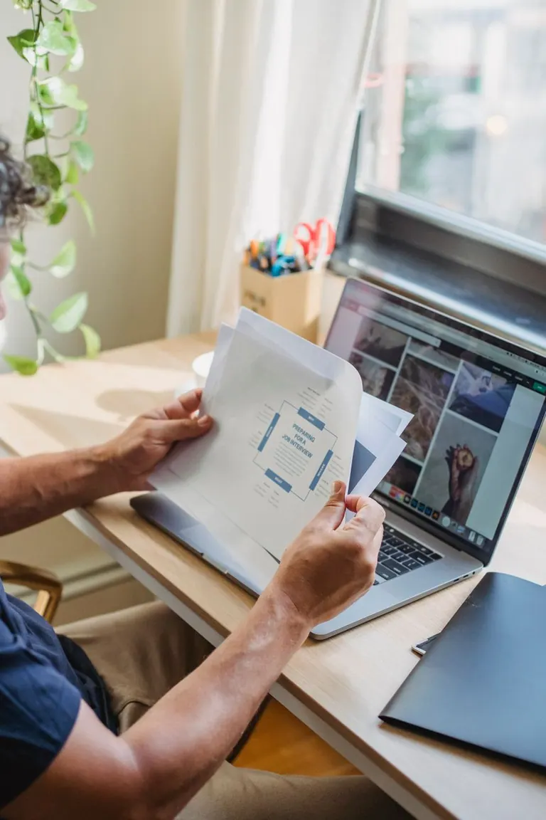 Un professionnel travaillant à distance, révisant des documents tout en utilisant un ordinateur portable dans un espace de Un professionnel travaillant à distance, révisant des documents tout en utilisant un ordinateur portable dans un espace de