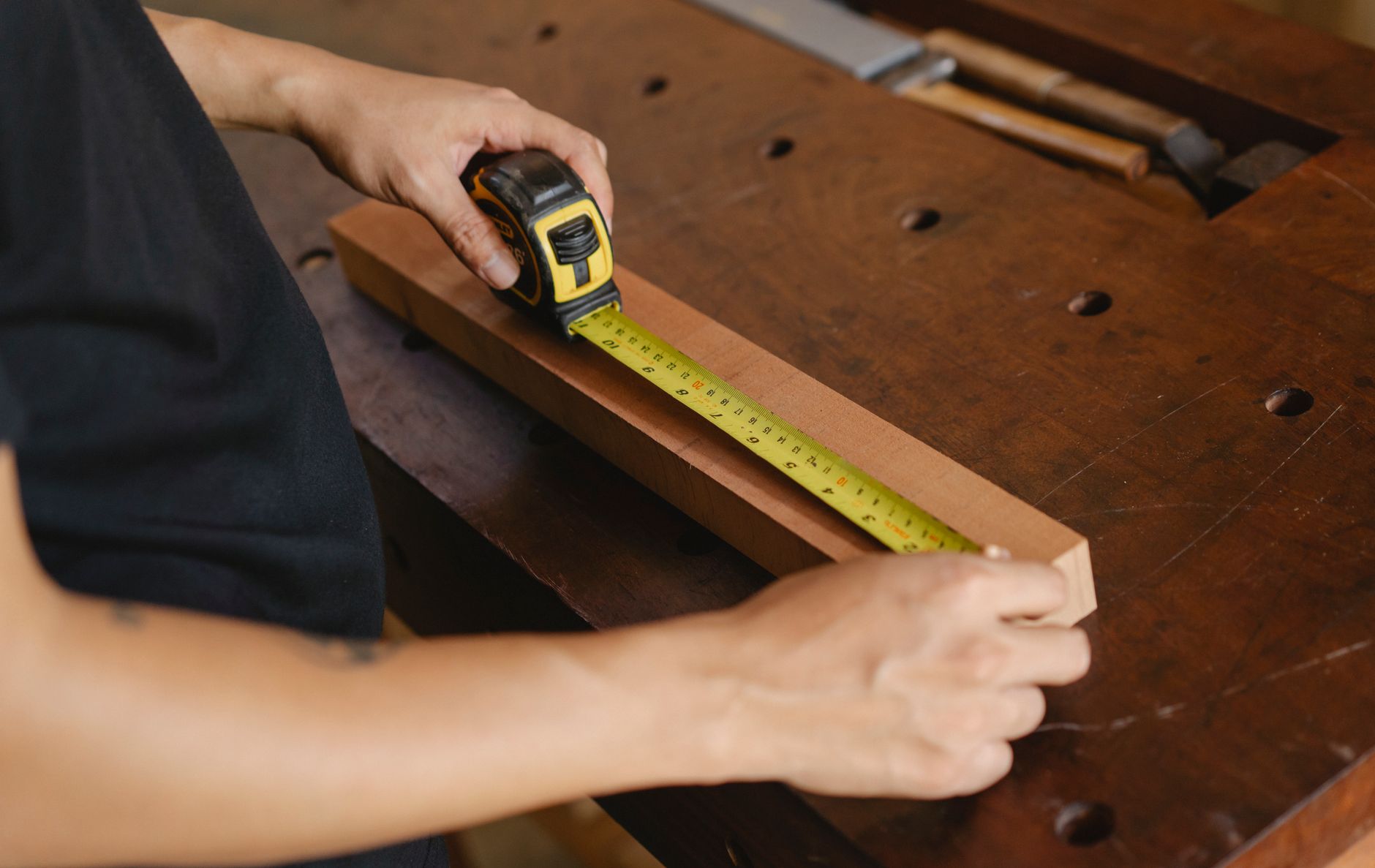 Artisan mesurant une pièce de bois dans son atelier