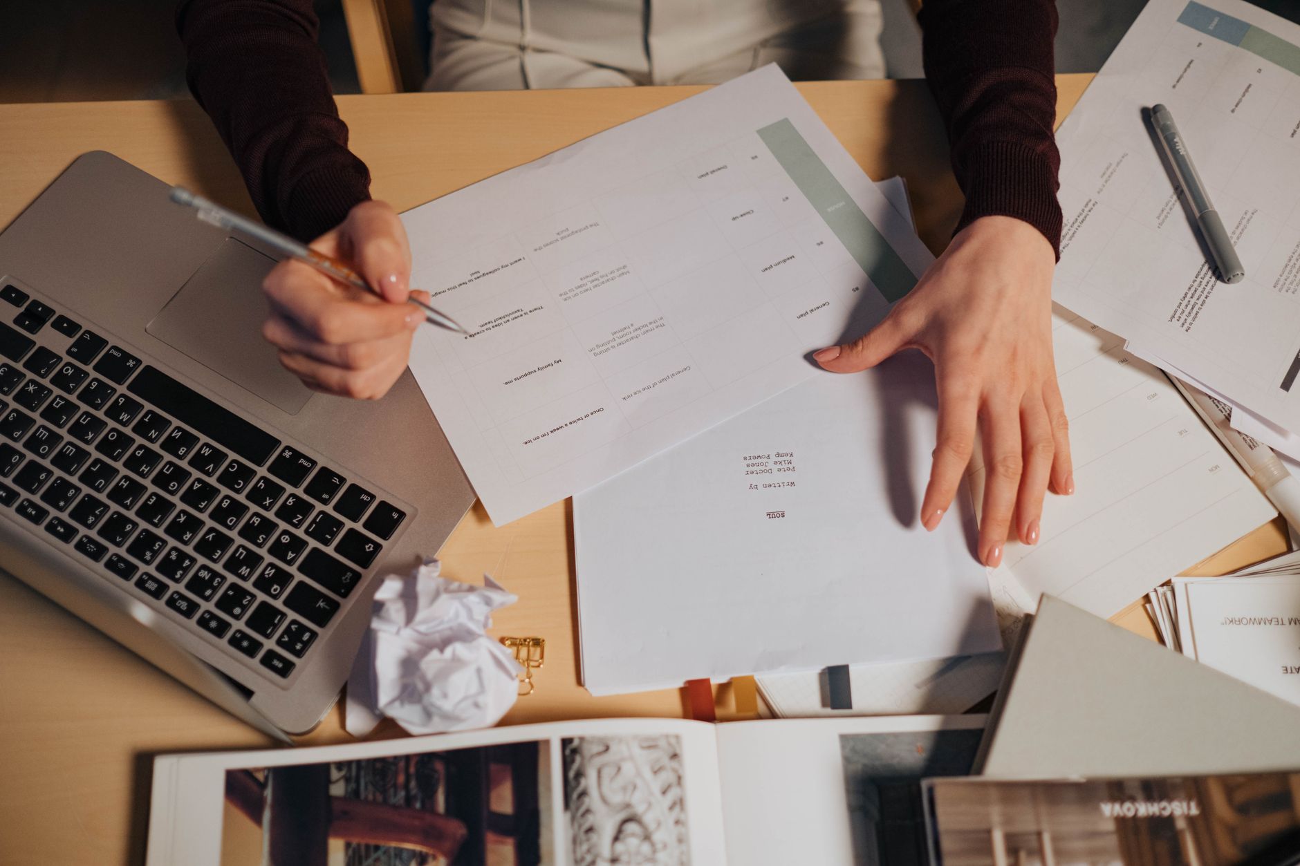 Indépendant prenant des notes sur son ordinateur portable entouré de documents administratifs.