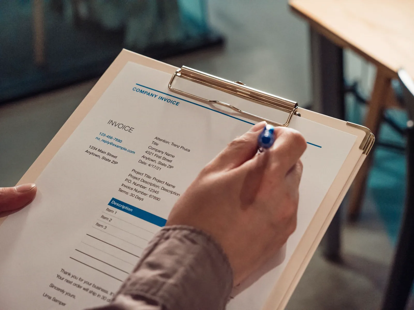 Main tenant une facture sur un presse-papiers avec un stylo, illustrant le format Factur-X.