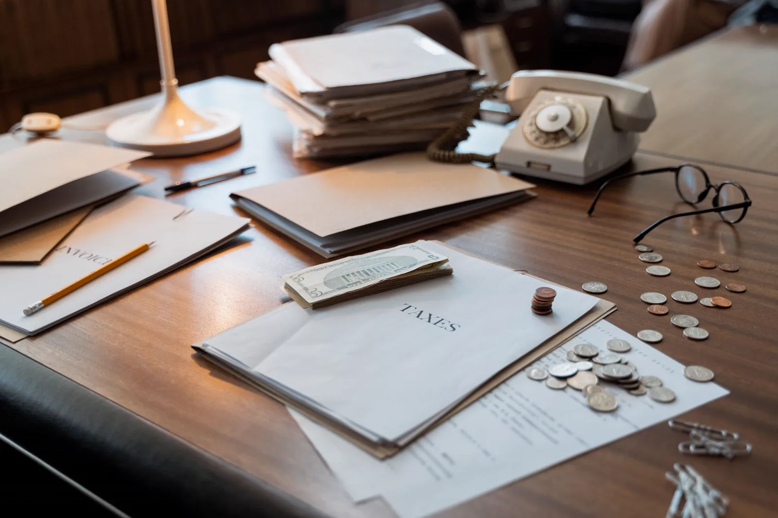 Bureau avec documents fiscaux, pièces de monnaie et lunettes, illustrant la TVA non récupérable.